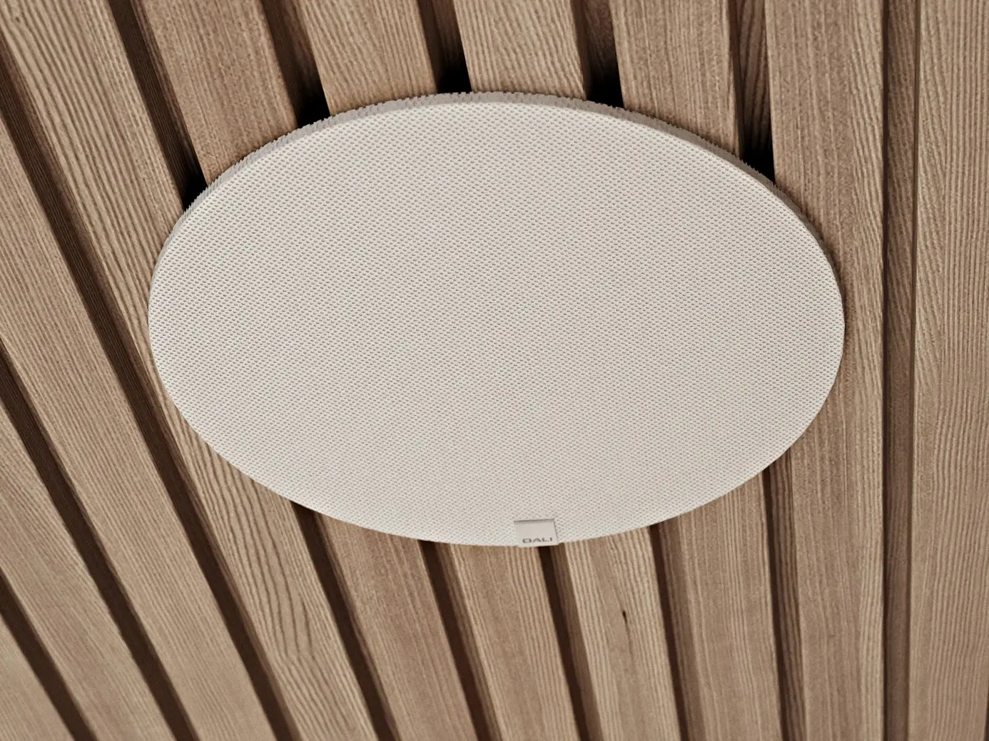 Dali Phantom E-80 WR: Se muestra el altavoz circular con su rejilla protectora, listo para instalar.