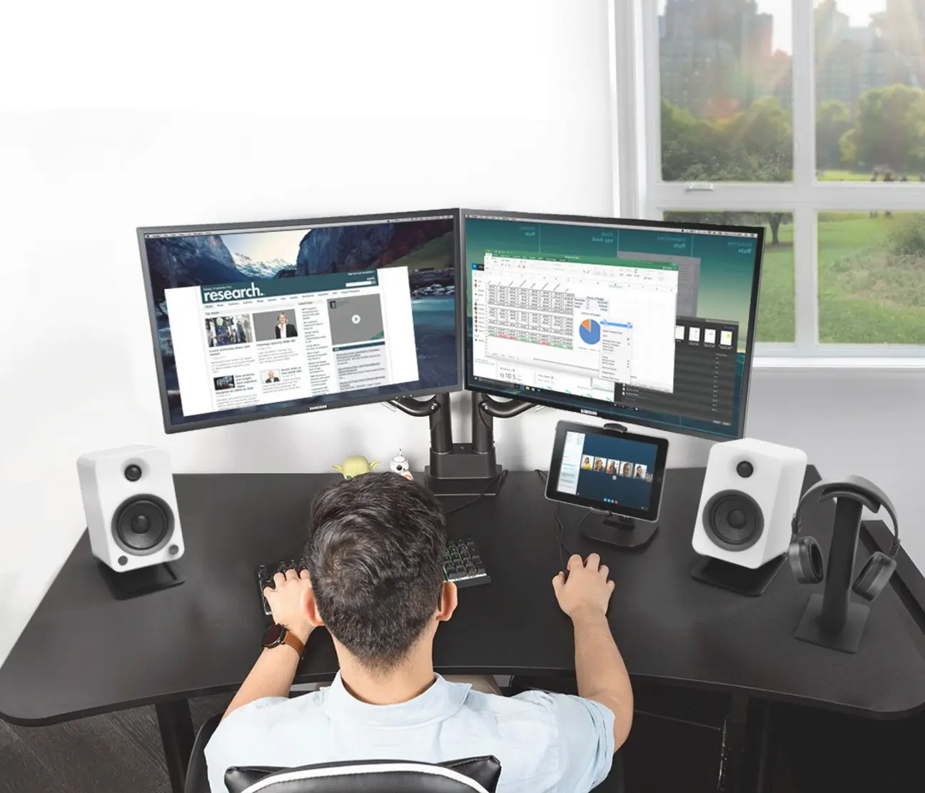 Kanto H2 Persona usando el Kanto H2 conectado a un soporte, mientras trabaja en dos monitores y un teclado.