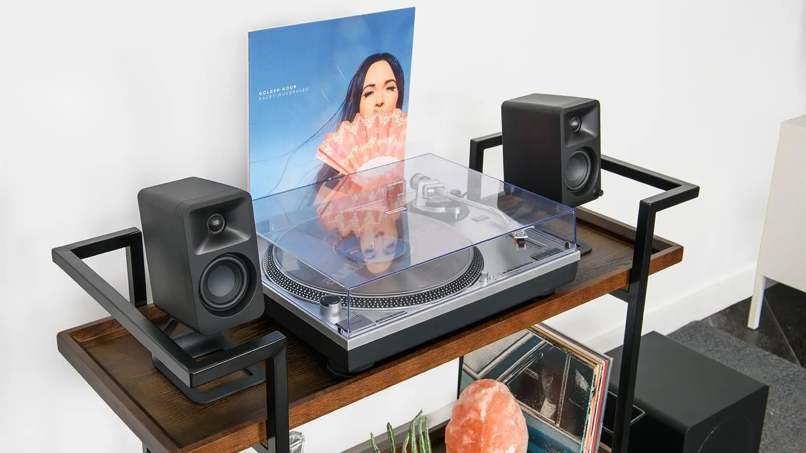 Vista frontal del Kanto ORA mostrando altavoces junto a tocadiscos con cubierta transparente incluida.