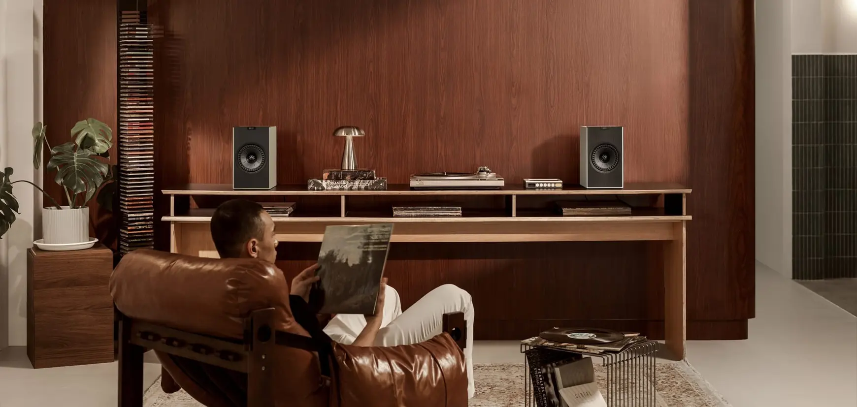 Kef Coda W Persona con el producto Kef Coda W en una estantería, vista frontal, mostrando los altavoces en uso.